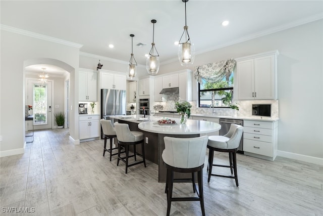 kitchen with white cabinets, stainless steel appliances, pendant lighting, and a kitchen island