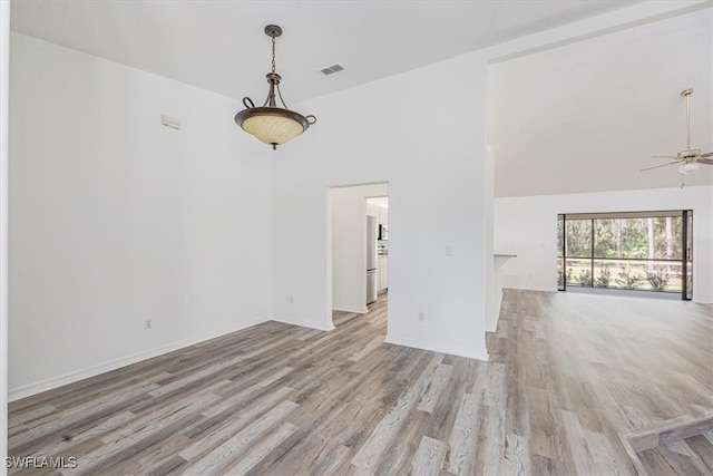 empty room featuring ceiling fan, high vaulted ceiling, and light hardwood / wood-style flooring