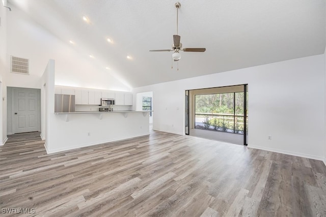 unfurnished living room featuring light wood-type flooring, high vaulted ceiling, and ceiling fan