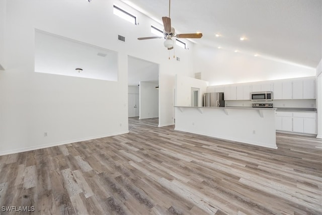 unfurnished living room with high vaulted ceiling, light wood-type flooring, and ceiling fan