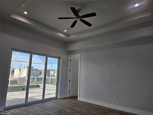 unfurnished room featuring ceiling fan, dark wood-type flooring, and a raised ceiling