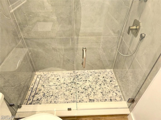 bathroom with a shower with door and toilet