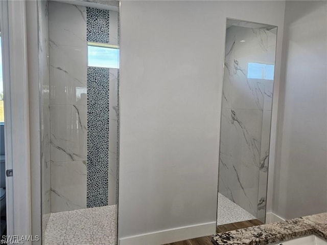 bathroom with a tile shower, hardwood / wood-style flooring, and toilet