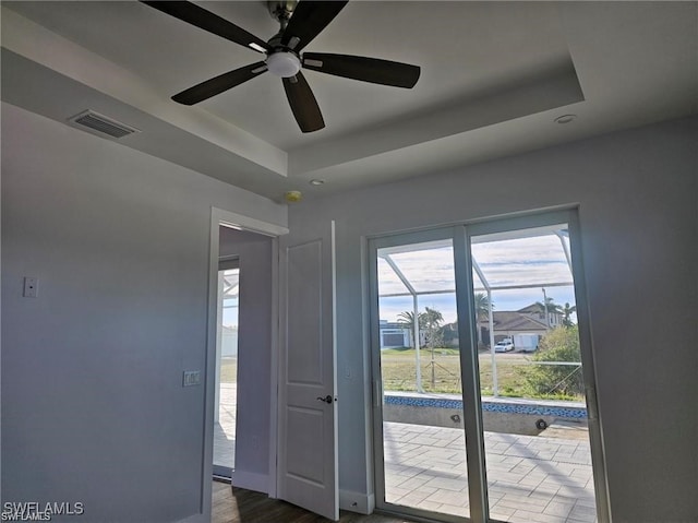 doorway featuring ceiling fan, hardwood / wood-style flooring, and a tray ceiling