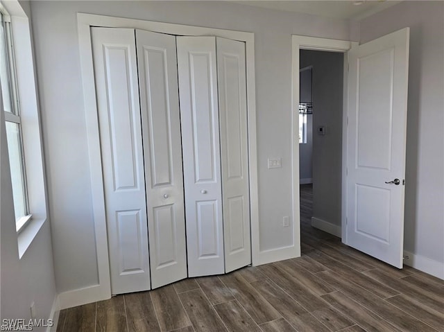 unfurnished bedroom with dark wood-type flooring and a closet