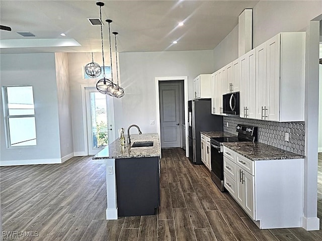 kitchen featuring a kitchen island with sink, stainless steel range with electric stovetop, sink, decorative light fixtures, and dark hardwood / wood-style flooring