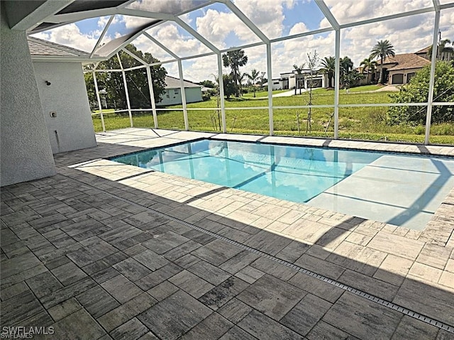 view of swimming pool with a yard, a patio area, and glass enclosure