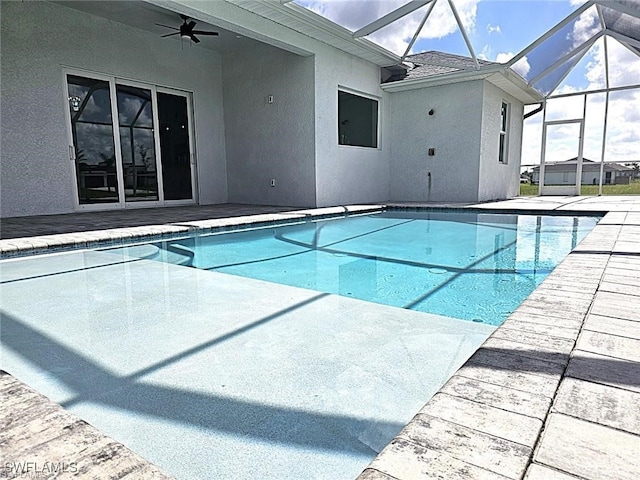 view of swimming pool featuring a patio area, glass enclosure, and ceiling fan