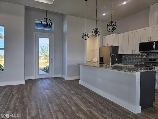 kitchen with appliances with stainless steel finishes, white cabinets, and an island with sink