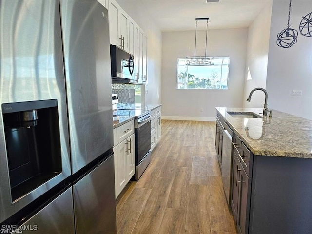 kitchen with hanging light fixtures, appliances with stainless steel finishes, sink, and white cabinets