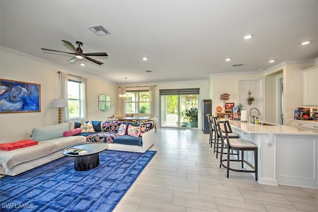 living room with crown molding, sink, ceiling fan with notable chandelier, and plenty of natural light