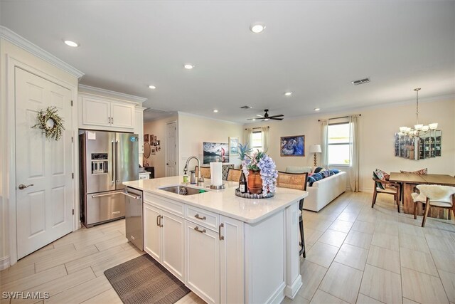 kitchen with white cabinets, a kitchen island with sink, sink, pendant lighting, and stainless steel appliances