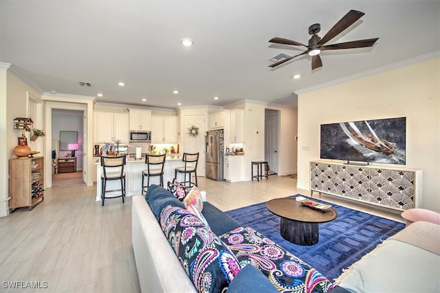 living room featuring ornamental molding, light wood-type flooring, and ceiling fan