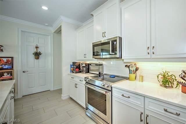 kitchen with white cabinets, light stone counters, backsplash, ornamental molding, and stainless steel appliances