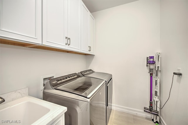 laundry room featuring cabinets, light hardwood / wood-style flooring, sink, and washing machine and clothes dryer