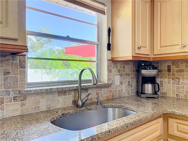 kitchen with light stone countertops, sink, light brown cabinetry, and tasteful backsplash