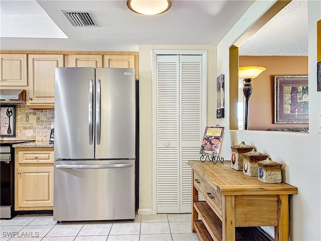 kitchen featuring ventilation hood, light tile patterned floors, light brown cabinetry, and stainless steel refrigerator