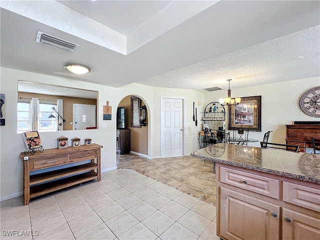 kitchen featuring dark stone countertops, light tile patterned floors, a textured ceiling, decorative light fixtures, and a chandelier