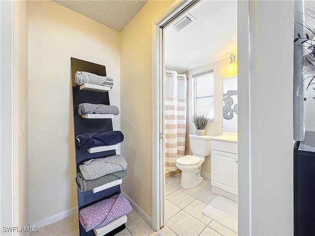 bathroom featuring vanity, tile patterned flooring, toilet, walk in shower, and a textured ceiling