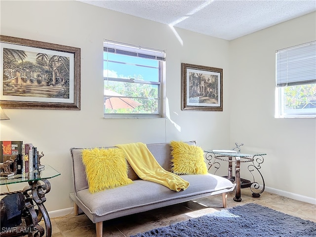 living area with plenty of natural light, a textured ceiling, and tile patterned flooring