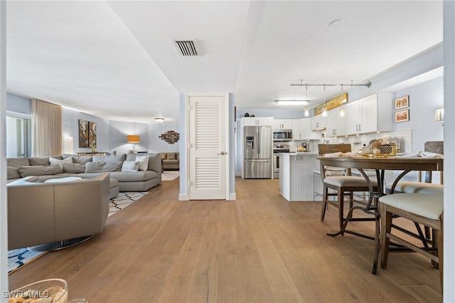 dining area featuring rail lighting and light hardwood / wood-style flooring