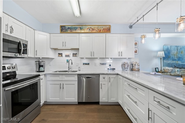 kitchen with appliances with stainless steel finishes, sink, white cabinets, decorative backsplash, and hanging light fixtures