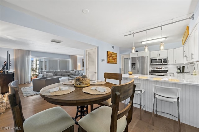 dining space featuring dark hardwood / wood-style flooring, sink, and rail lighting