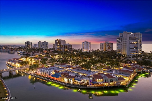 aerial view at dusk featuring a city view and a water view