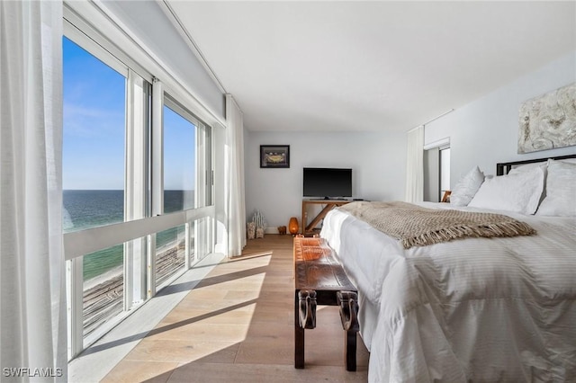 bedroom with wood finished floors and a water view