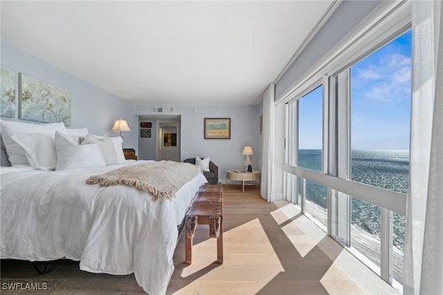 bedroom featuring multiple windows, a water view, and hardwood / wood-style flooring