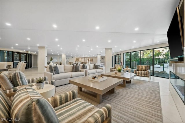 living room featuring a wall of windows, decorative columns, and light tile patterned floors