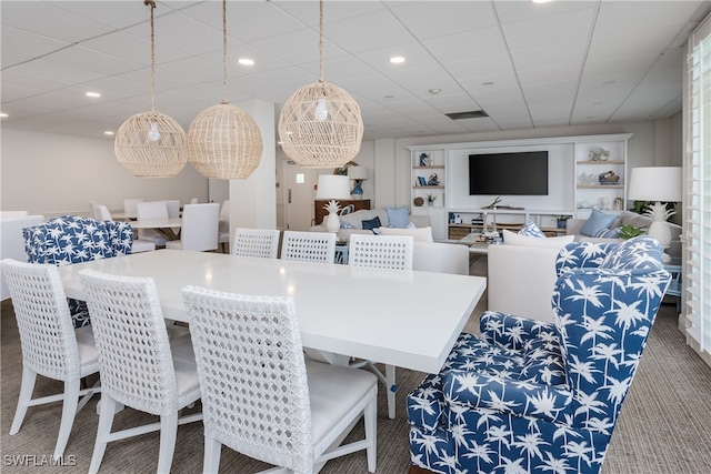 carpeted dining space with a drop ceiling