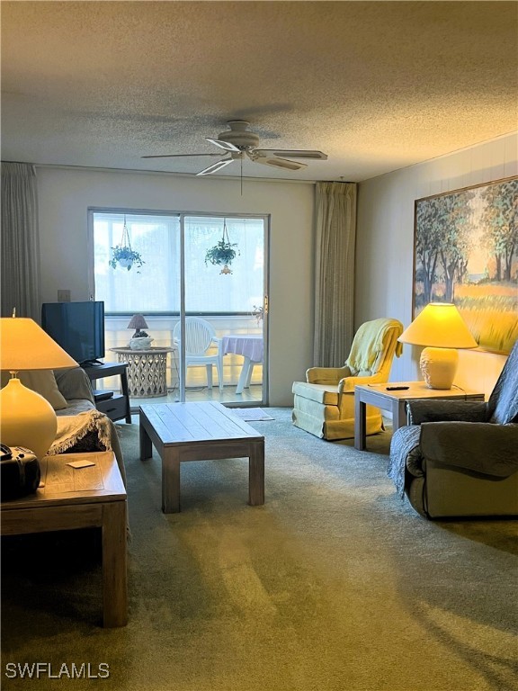 living room with a textured ceiling, carpet floors, and ceiling fan