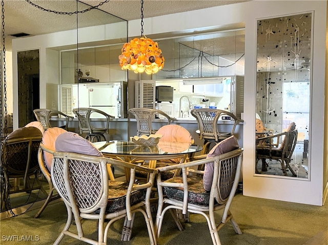 dining area featuring a textured ceiling, sink, and carpet flooring