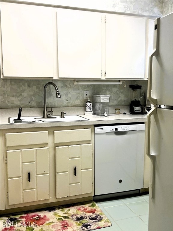 kitchen featuring tasteful backsplash, sink, light tile patterned floors, and white appliances