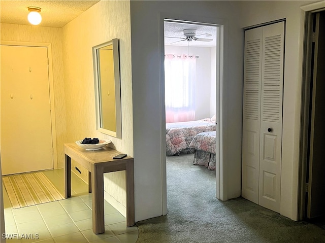 hallway with light carpet and a textured ceiling