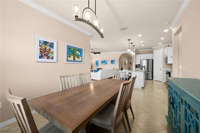 tiled dining room with ceiling fan with notable chandelier and ornamental molding