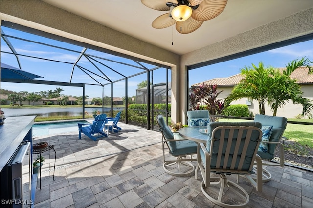 view of patio / terrace with a lanai, ceiling fan, and a water view