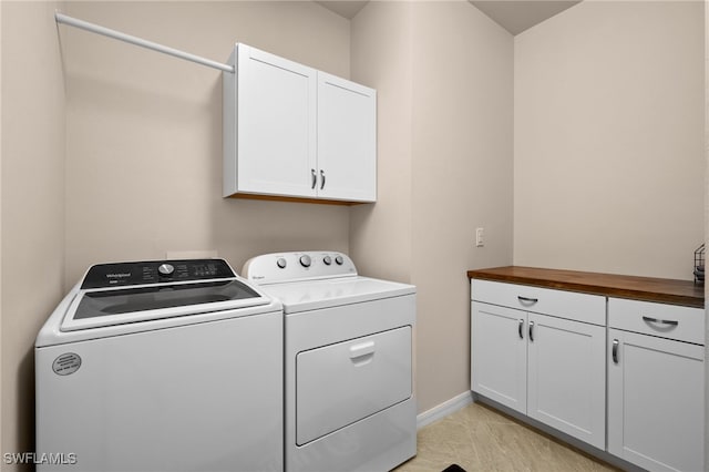 clothes washing area with washer and clothes dryer and cabinets