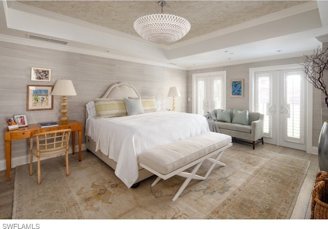 bedroom featuring french doors, wood-type flooring, crown molding, an inviting chandelier, and a raised ceiling