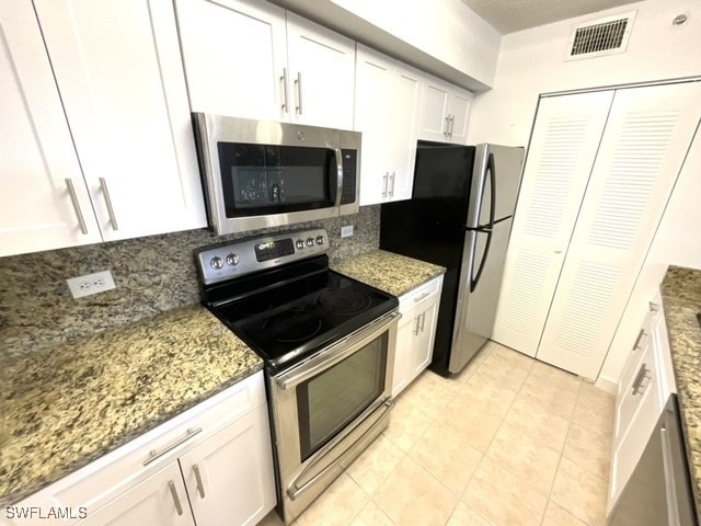 kitchen featuring white cabinetry, stainless steel appliances, and dark stone counters