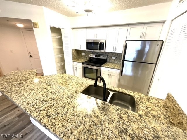 kitchen with light stone countertops, appliances with stainless steel finishes, and white cabinets