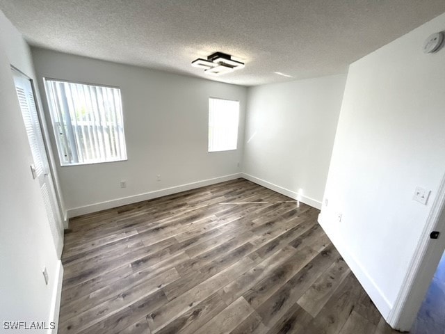 spare room with dark wood-type flooring, a textured ceiling, and plenty of natural light