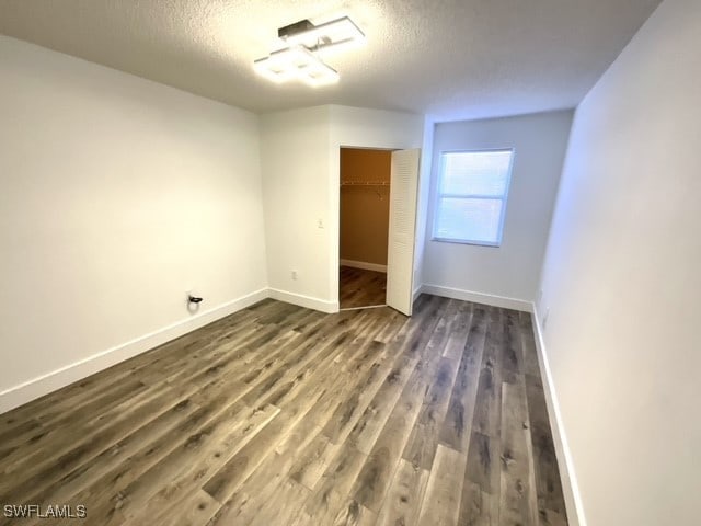 unfurnished bedroom featuring a closet, dark wood-type flooring, and a textured ceiling