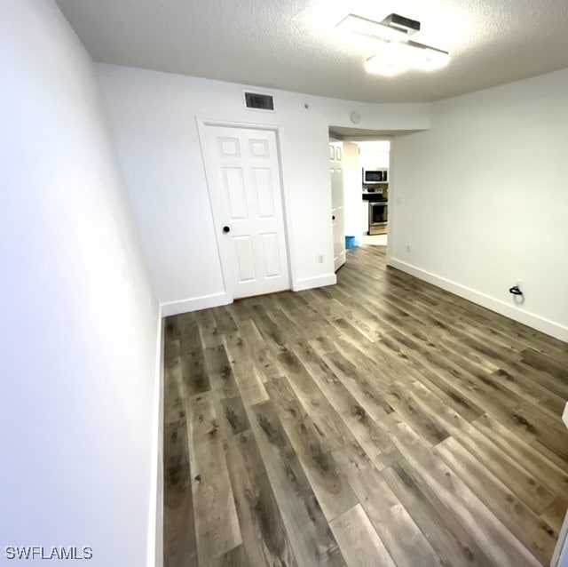 empty room with a textured ceiling and dark hardwood / wood-style flooring