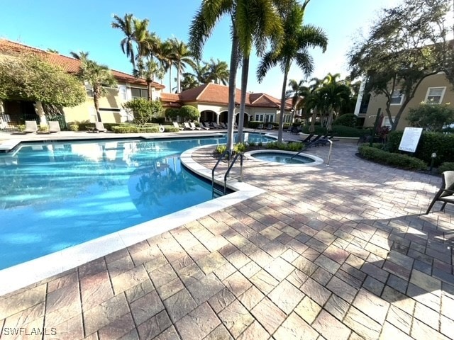 view of swimming pool featuring a hot tub and a patio