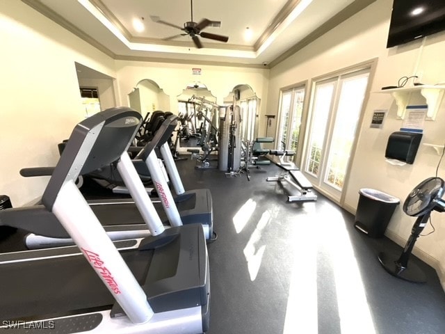 gym featuring ornamental molding, a tray ceiling, and ceiling fan