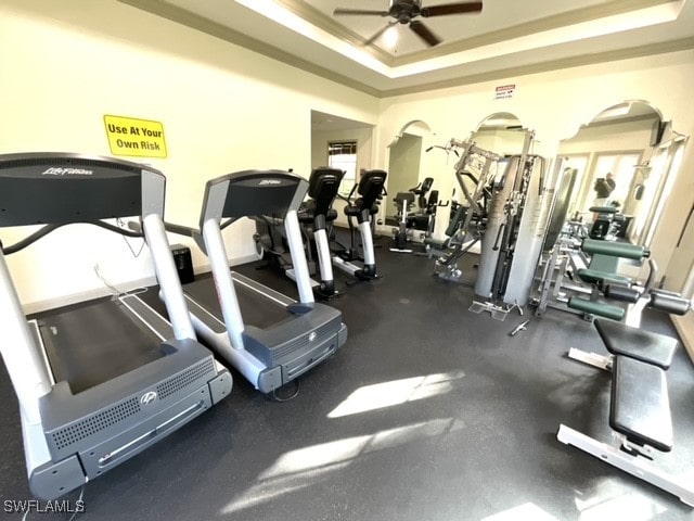 exercise room with crown molding, a raised ceiling, and ceiling fan