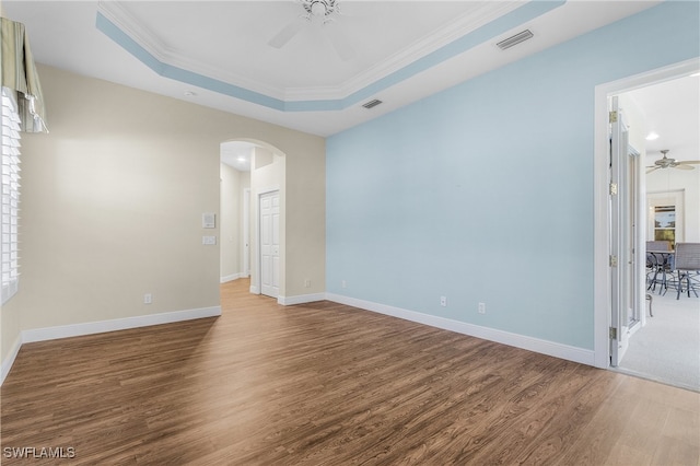 unfurnished room with hardwood / wood-style floors, crown molding, ceiling fan, and a raised ceiling