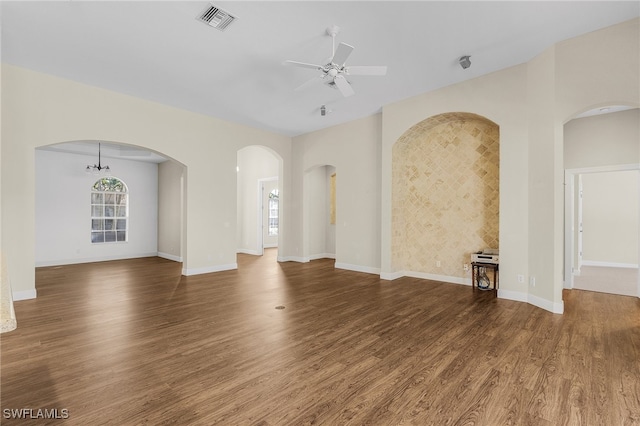 unfurnished living room with dark wood-type flooring and ceiling fan with notable chandelier